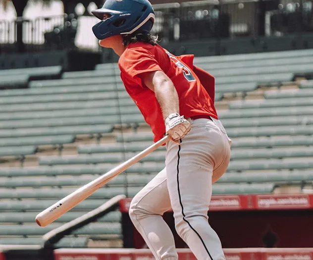 A baseball player gets ready to run after making a hit.