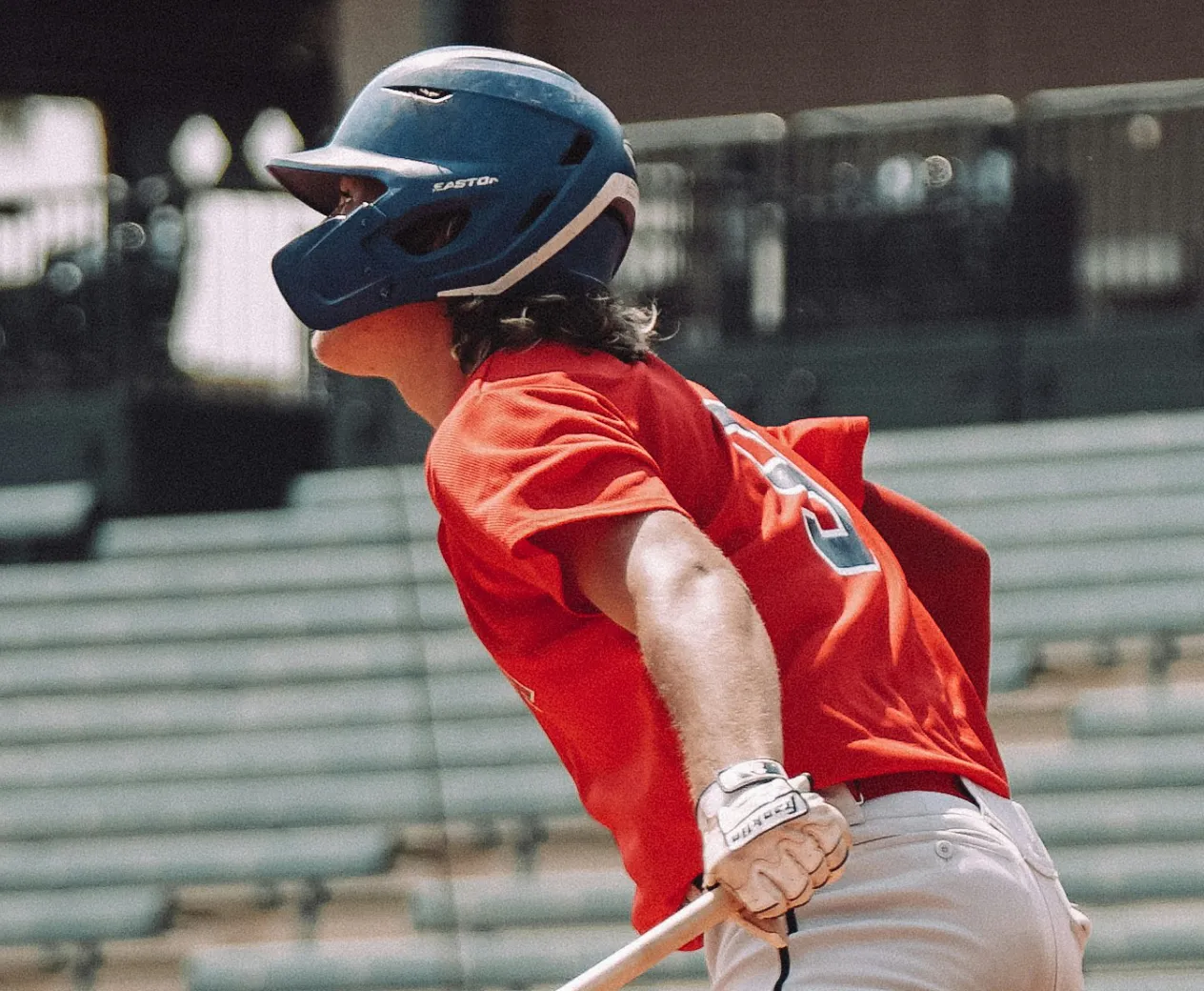 A baseball player gets ready to run after making a hit.