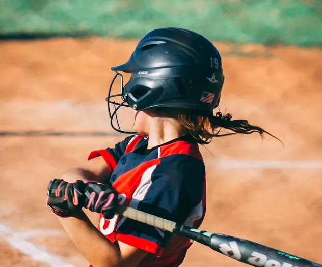 A softball player swings at a pitch.