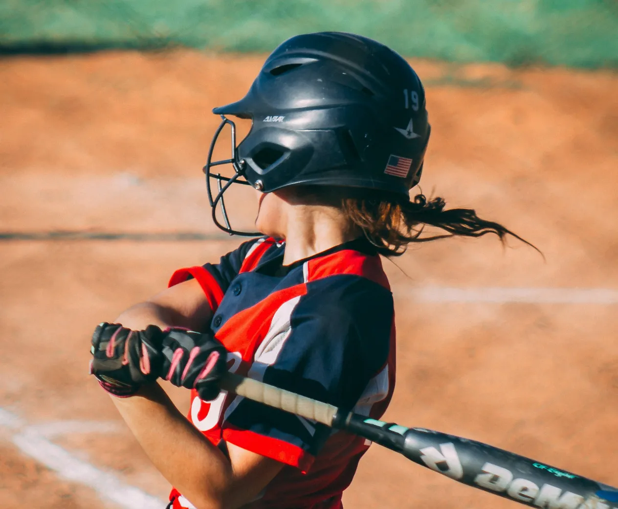 A softball player swings at a pitch.